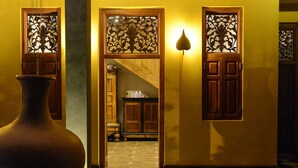 A hallway with a large vase, a checkered floor, and wooden doors with decorative glass panels. - Olcote in Ceylon (Piliyandala)