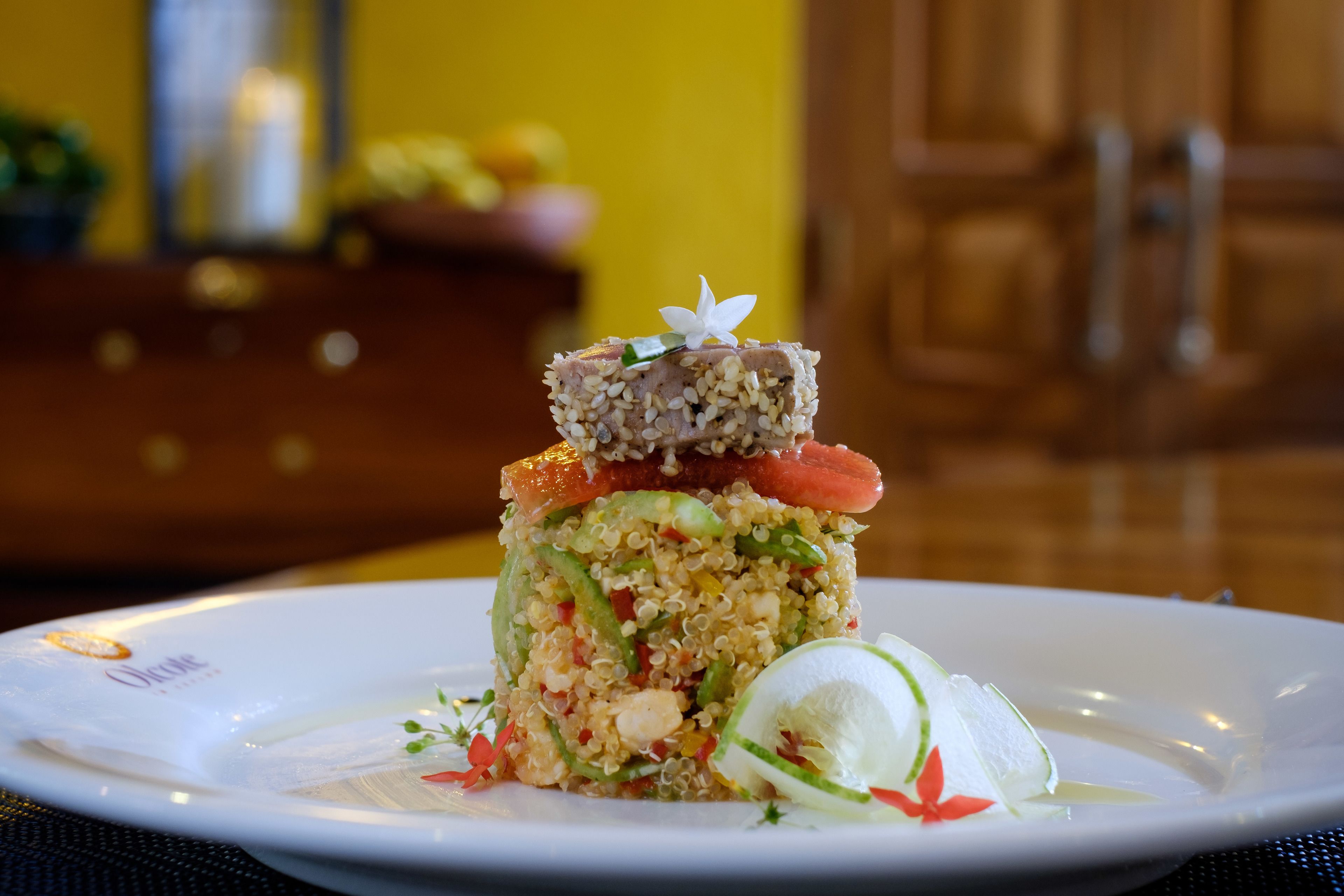 Ein Teller mit Quinoa, Gemüse und einer dekorativen Garnitur.