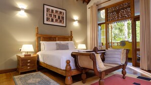 A bedroom with a large bed, wooden headboard, bedside tables with lamps, a chair, and a large window with curtains. - Olcote in Ceylon (Piliyandala)