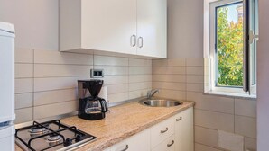 Une cuisine compacte équipée d’une cuisinière à gaz, d’une machine à café, d’un évier et de placards.