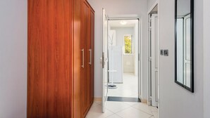 Un couloir avec une armoire en bois, un miroir et une salle de bain visible à travers une porte ouverte.
