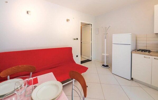A compact living space with a kitchenette, a dining area with a red sofa, and a white refrigerator. - Awesome apartment in Opatija (Opatija)