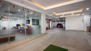 A modern hotel lobby with glass walls, a reception desk, and a car parked in the background. - Aparthanoi (Hanoi)