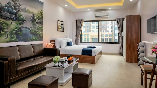 A modern hotel room with a large bed, a sofa, a coffee table, and a desk. - Aparthanoi (Hanoi)