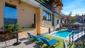 A poolside area with a pool, blue lounge chairs, and a small table. - Gorgeous home in Vele Mune (Vele Mune)