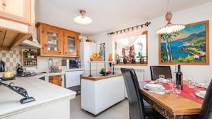 A kitchen with wooden cabinets, a microwave, and a dining area with a table set for two. - Gorgeous home in Vele Mune (Vele Mune)