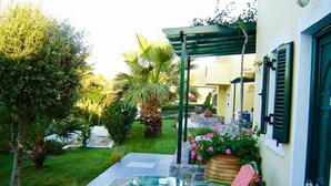 A patio with a glass table and chairs, surrounded by lush greenery and a pergola. - Sunrise Apartments Hersonissos (Hersonissos)
