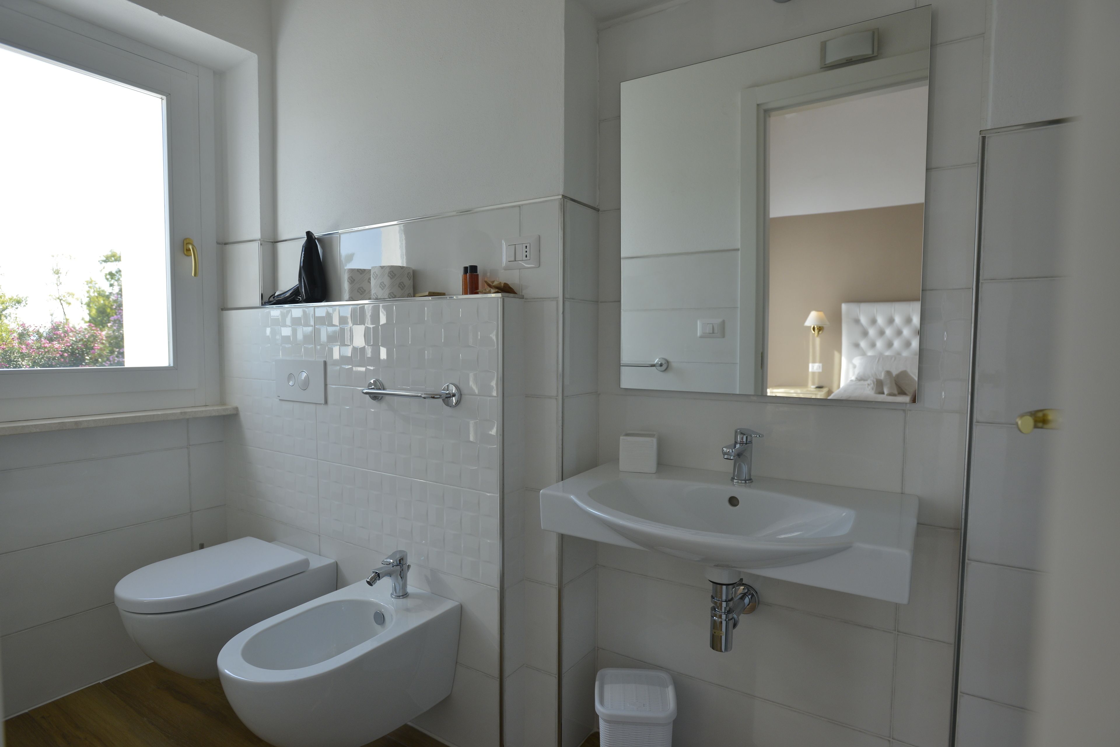 Een moderne badkamer met een hygiëneschuimer, toilet en wastafel.