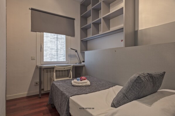 A compact bedroom with a bed, a desk, and a window. - Alcam Augusta (Barcelona)