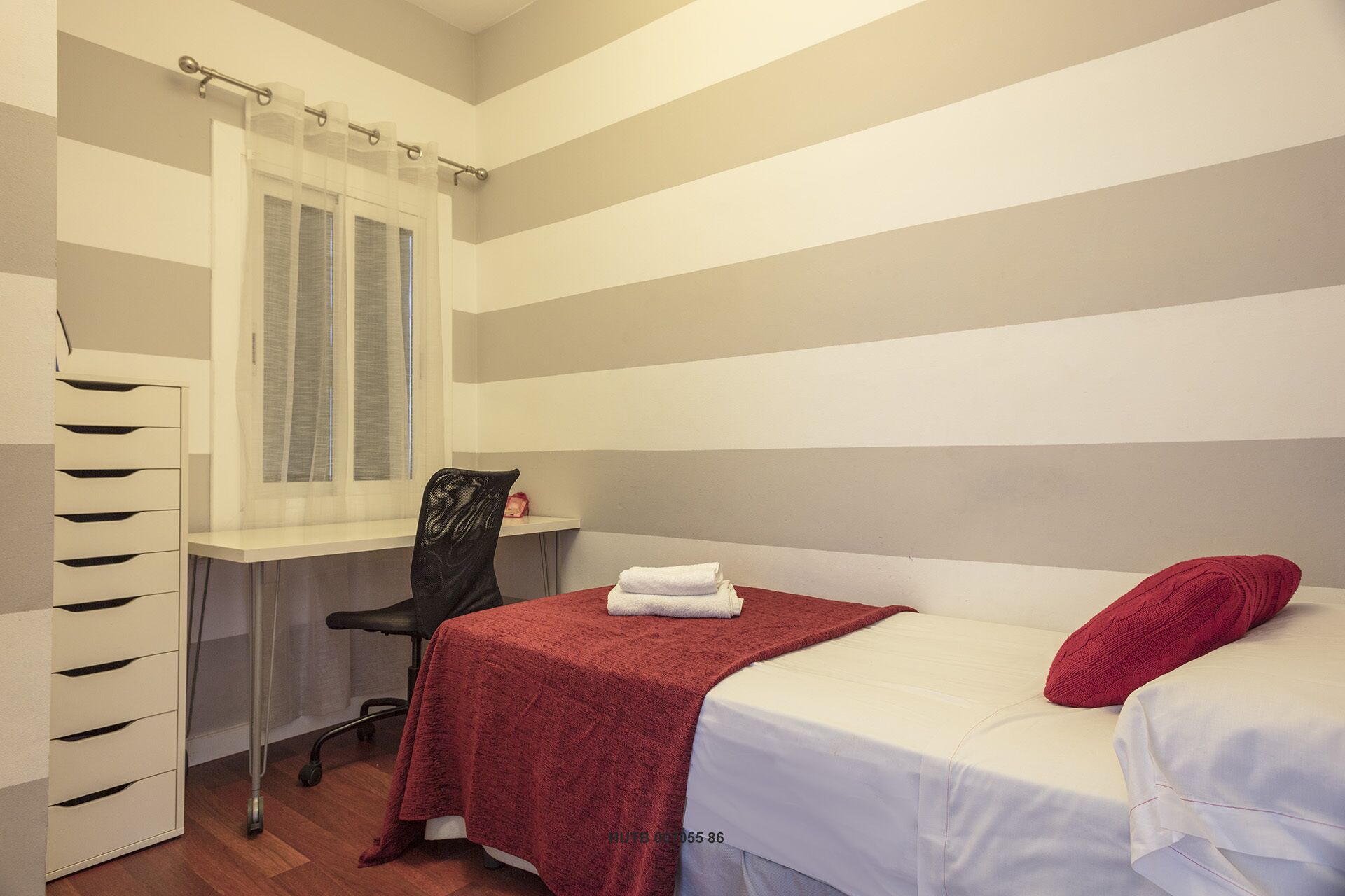 A bedroom with a bed, a desk, and a chair.