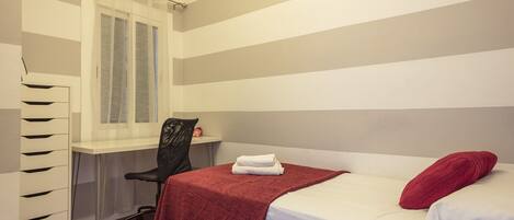 A bedroom with a bed, a desk, and a chair.