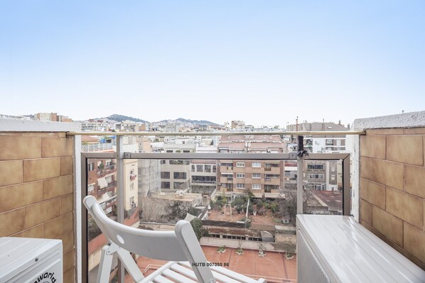 Ein Balkon mit Blick auf eine Stadtansicht, ein weißer Stuhl und eine weiße Heizung.