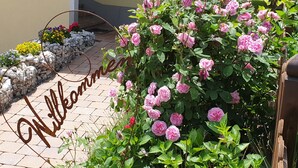 A garden with pink roses and a metal sign that reads "Willkommen". - Bed & Breakfast Mittelkärnten (Althofen)