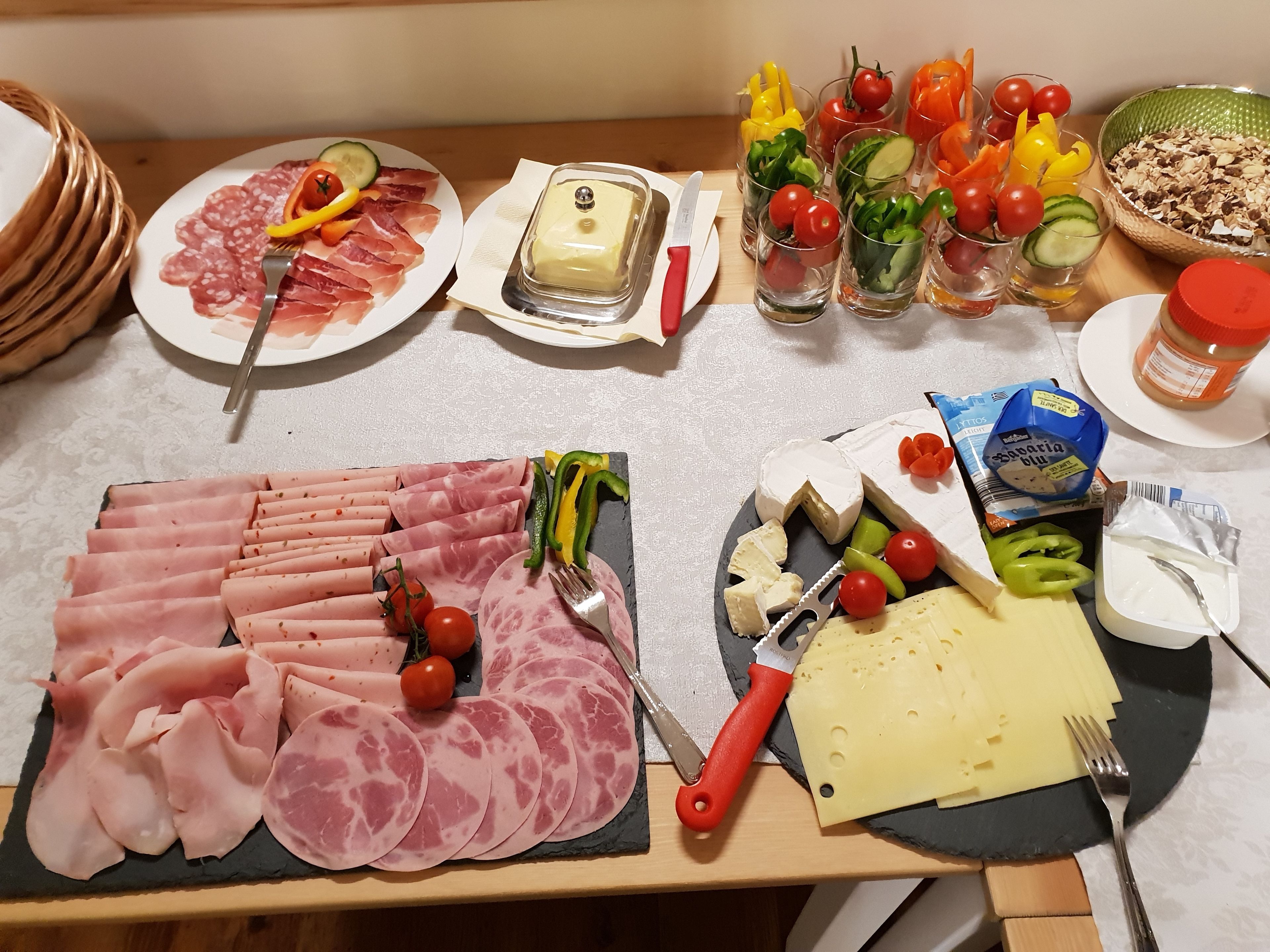 Una mesa con diversos alimentos, incluyendo carnes, quesos y verduras.