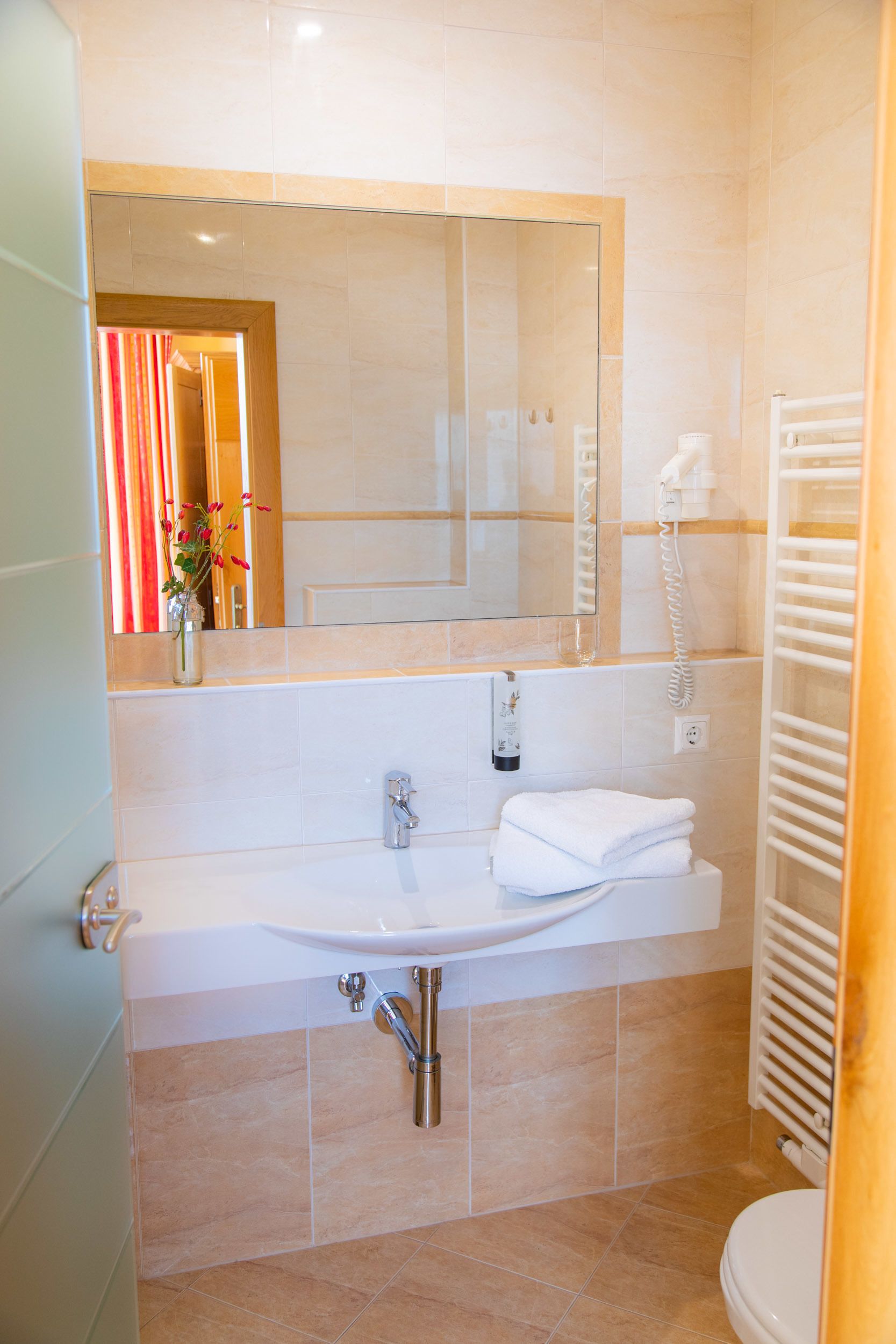 Un baño moderno con lavamanos, espejo y perchero.