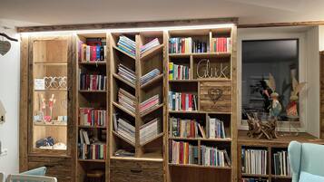 A room with a large wooden bookshelf filled with books, a small wooden desk, and a light blue armchair.
