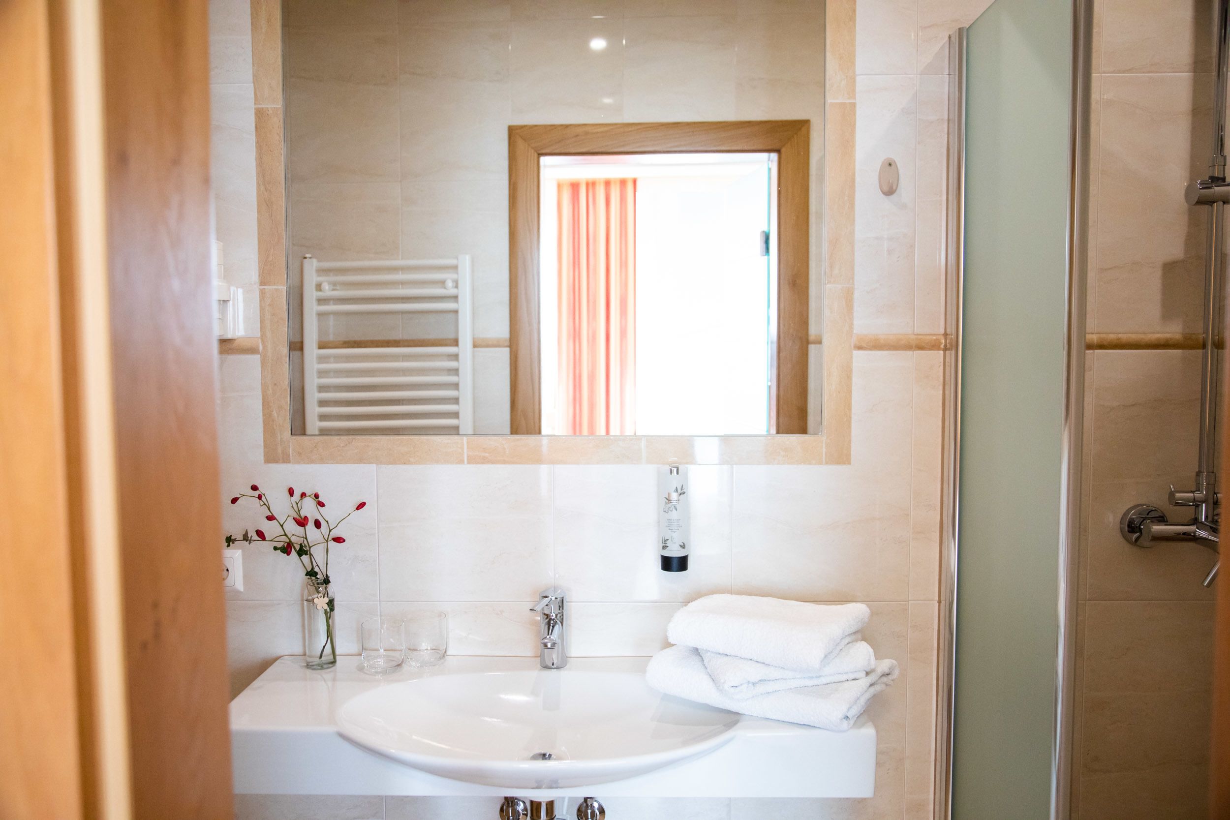 A bathroom with a white sink, a mirror, a towel rack, and a shower.
