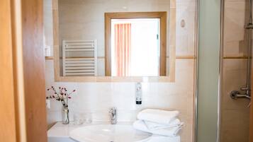 A bathroom with a white sink, a mirror, a towel rack, and a shower.