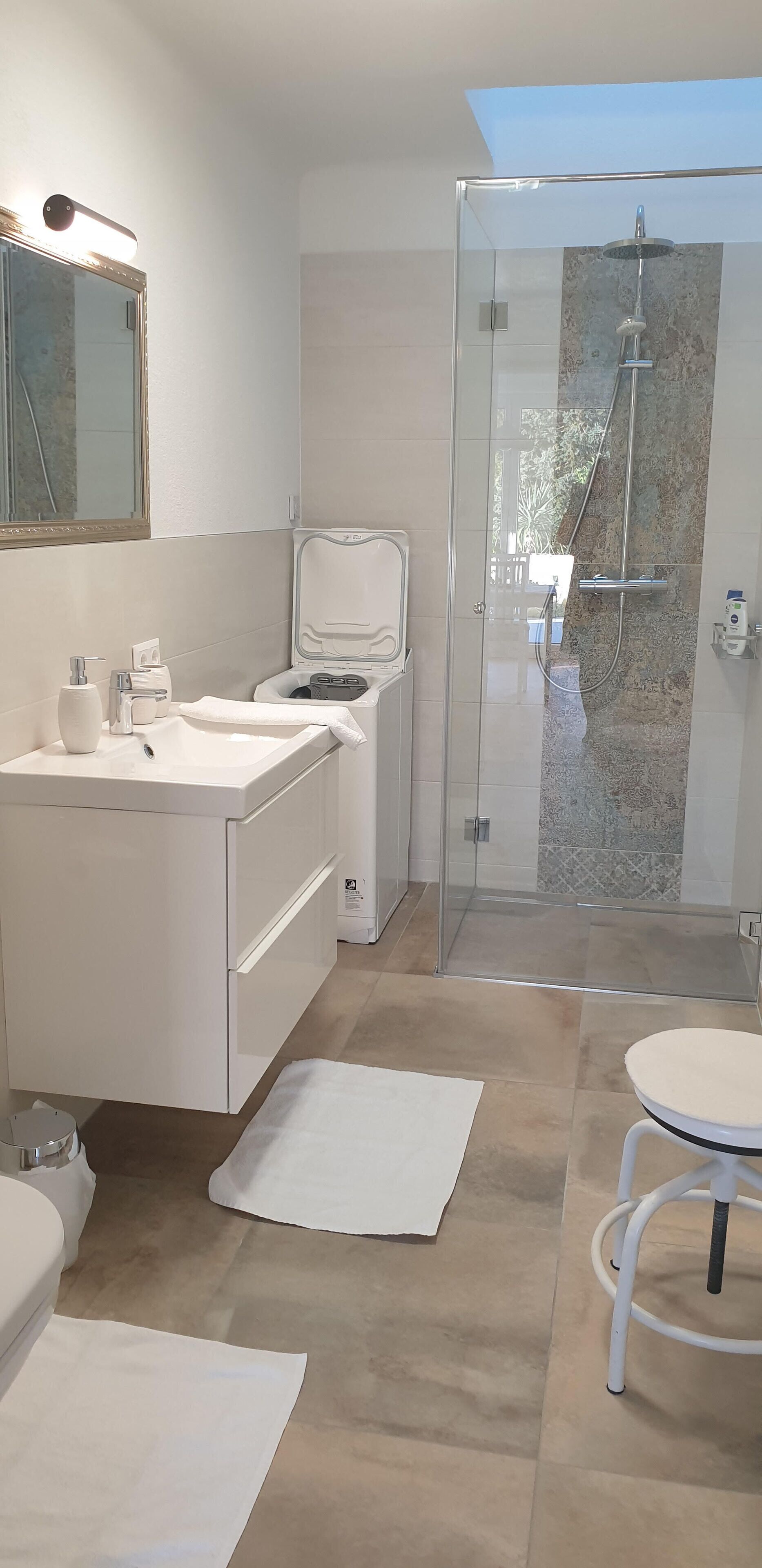 A modern bathroom with a glass-enclosed shower, a white sink, and a mirror above it.