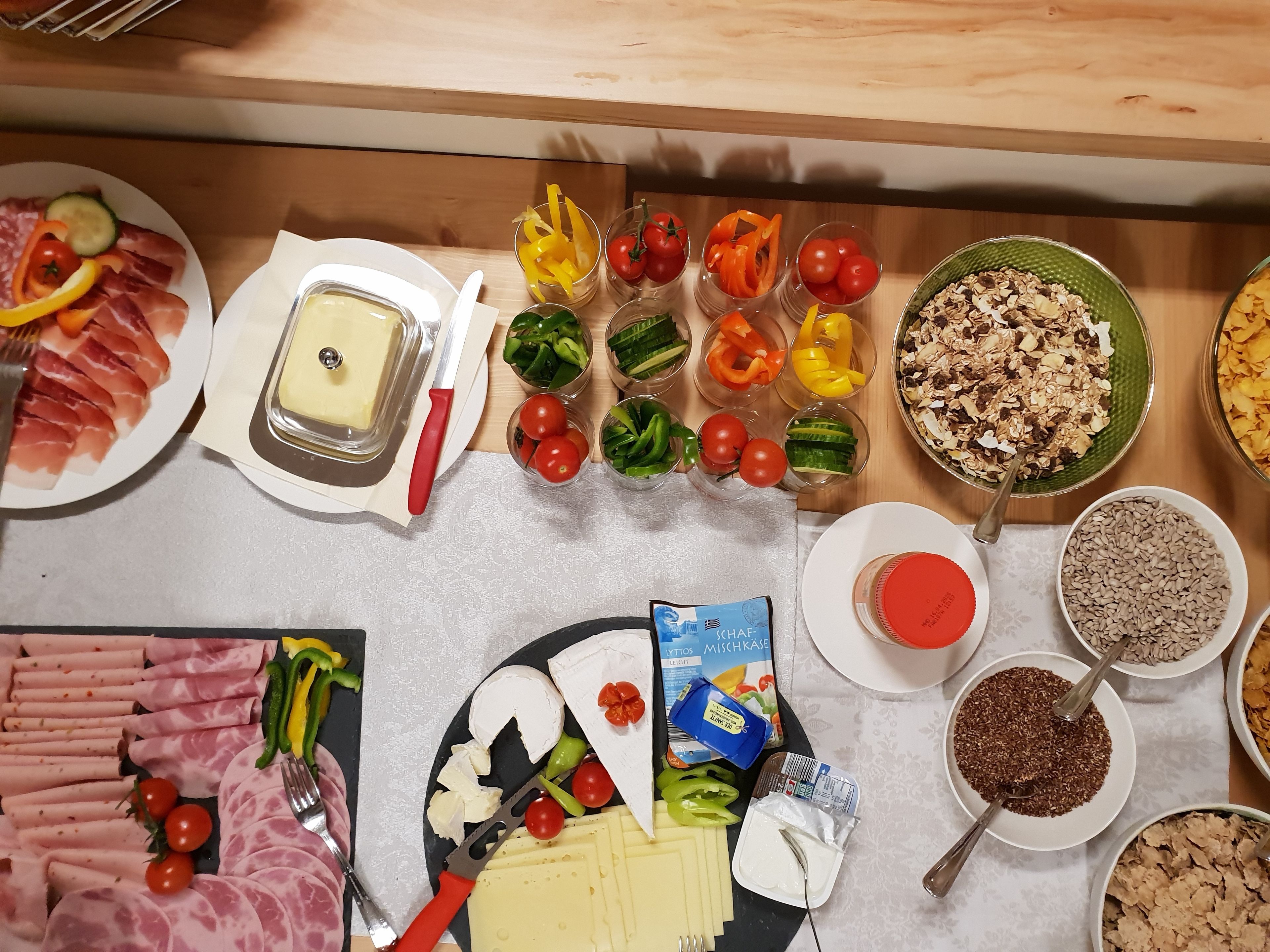 A buffet table with various food items including meats, cheeses, vegetables, and grains.