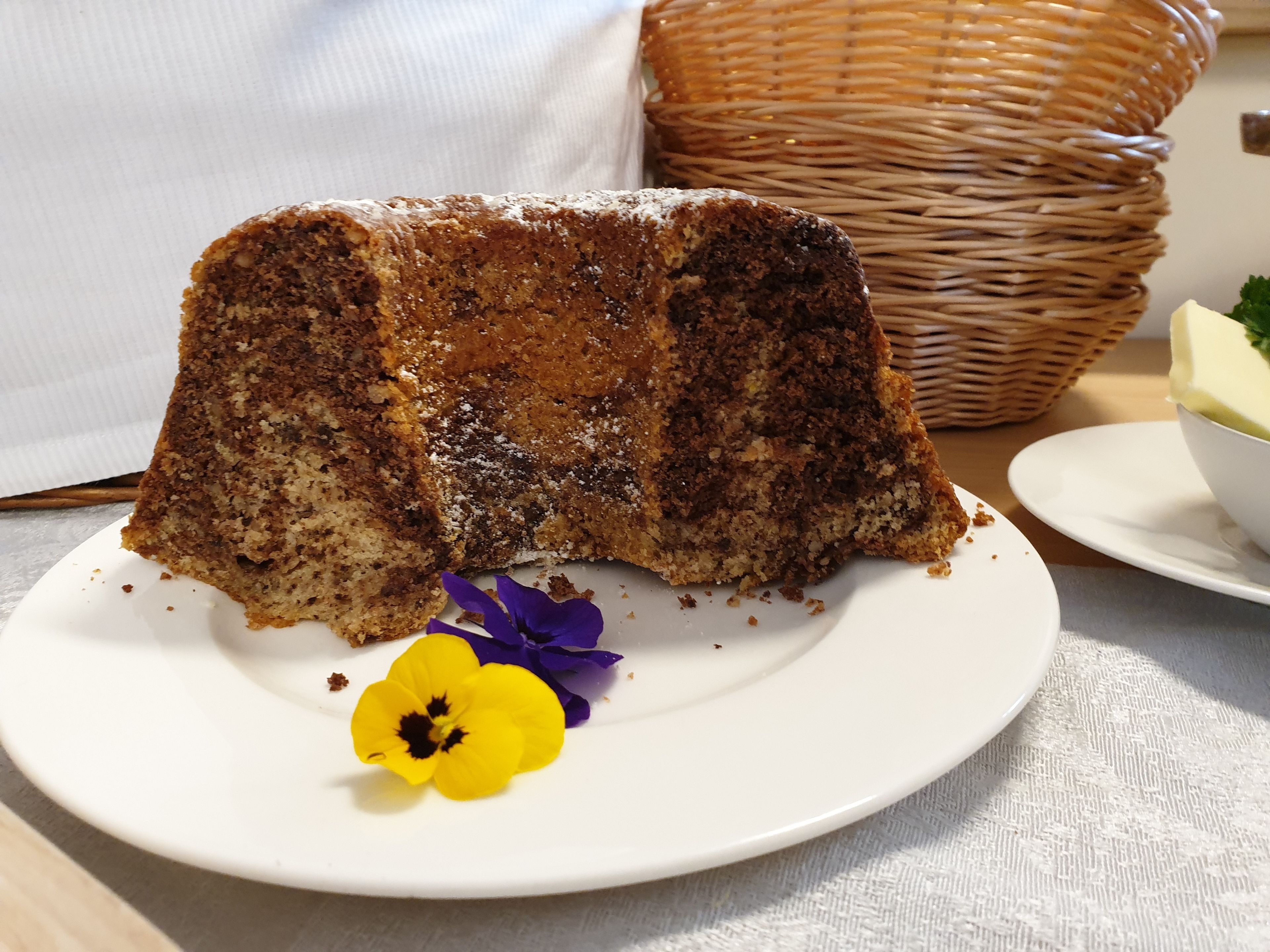Une part de gâteau sur une assiette blanche, avec une fleur jaune.