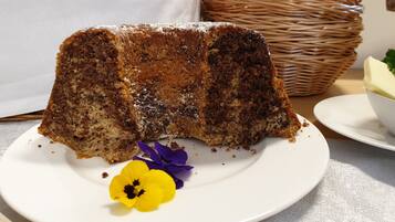 Une part de gâteau sur une assiette blanche, avec une fleur jaune.