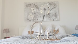 A neatly made bed with a patterned bedspread, a decorative wall piece above, and a bedside table with a lamp. - Bed & Breakfast Mittelkärnten (Althofen)