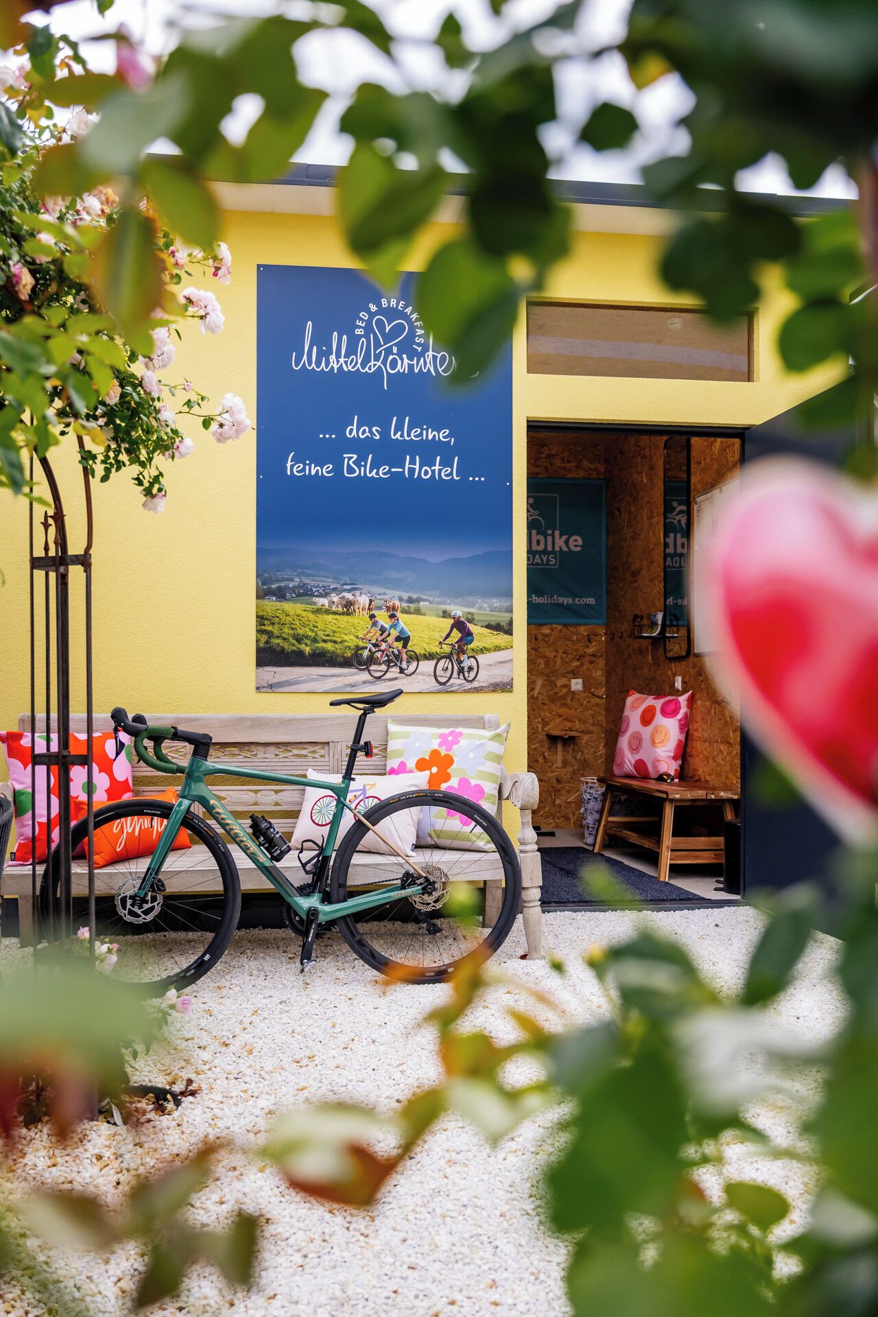 A bicycle parked in front of a building with a sign advertising a bike hotel.