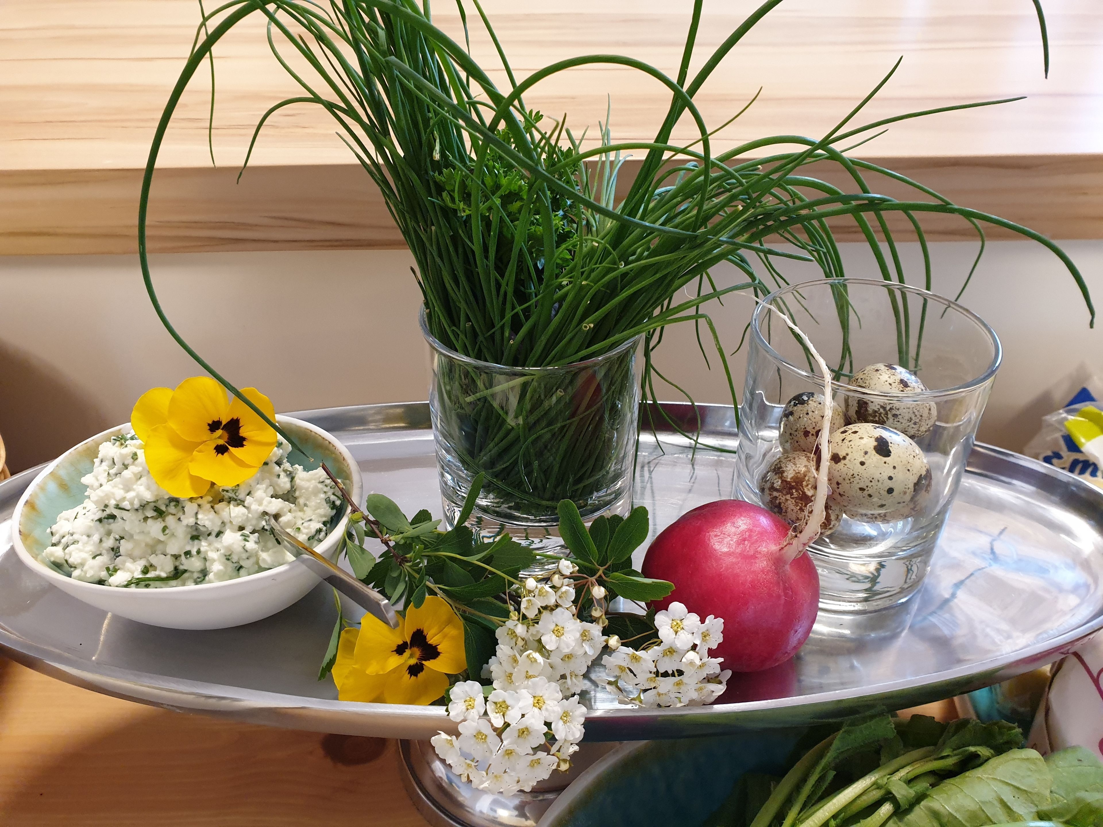 A tray with a bowl of cottage cheese, a pomegranate, and a glass of water with quail eggs.