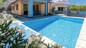 A modern house with a swimming pool, a covered patio, and a garden with white flowers. - Gorgeous home in Gostinjac (Gostinjac)