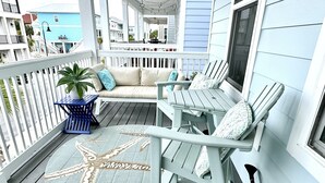 Een overdekt terras met een ronde vloerkleed, een zeester decoratie en een blauwe tafel.