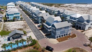 Een kustgebied met woonhuizen, meerdere tweelaagse huizen, een zwembad en een strand op de achtergrond.