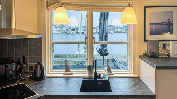 A kitchen with a large window, a black countertop, a kettle, a coffee maker, and a small potted plant. - Gorgeous home in Ebeltoft with WiFi (Ebeltoft)