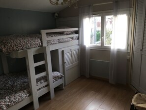 A room with bunk beds, a radiator, a window with curtains, and a wooden floor. - Beautifully furnished house with terraces G0254 (Lacanau)