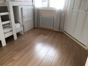 A room with a wooden floor, a radiator, a window with blinds, and a white wardrobe. - Beautifully furnished house with terraces G0254 (Lacanau)