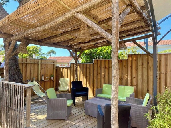 Eine Terrassengruppe mit Korbmöbeln, einer Pergola und einem Holzzaun.