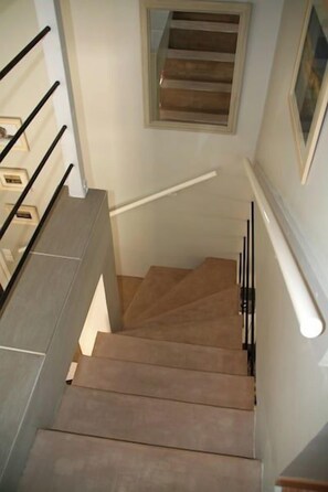 A staircase with wooden steps and black handrails, leading to a landing with a window. - Beautifully furnished house with terraces G0254 (Lacanau)