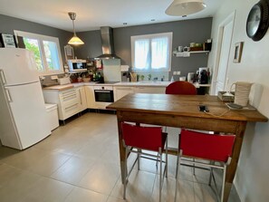 Une cuisine moderne avec des appareils électroménagers blancs, une table en bois et des chaises rouges.