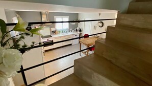 A staircase leading to a kitchen with white cabinets, a wooden table, and a red chair. - comfortable house in Lacanau Ocean, everything in walking distance (Lacanau)