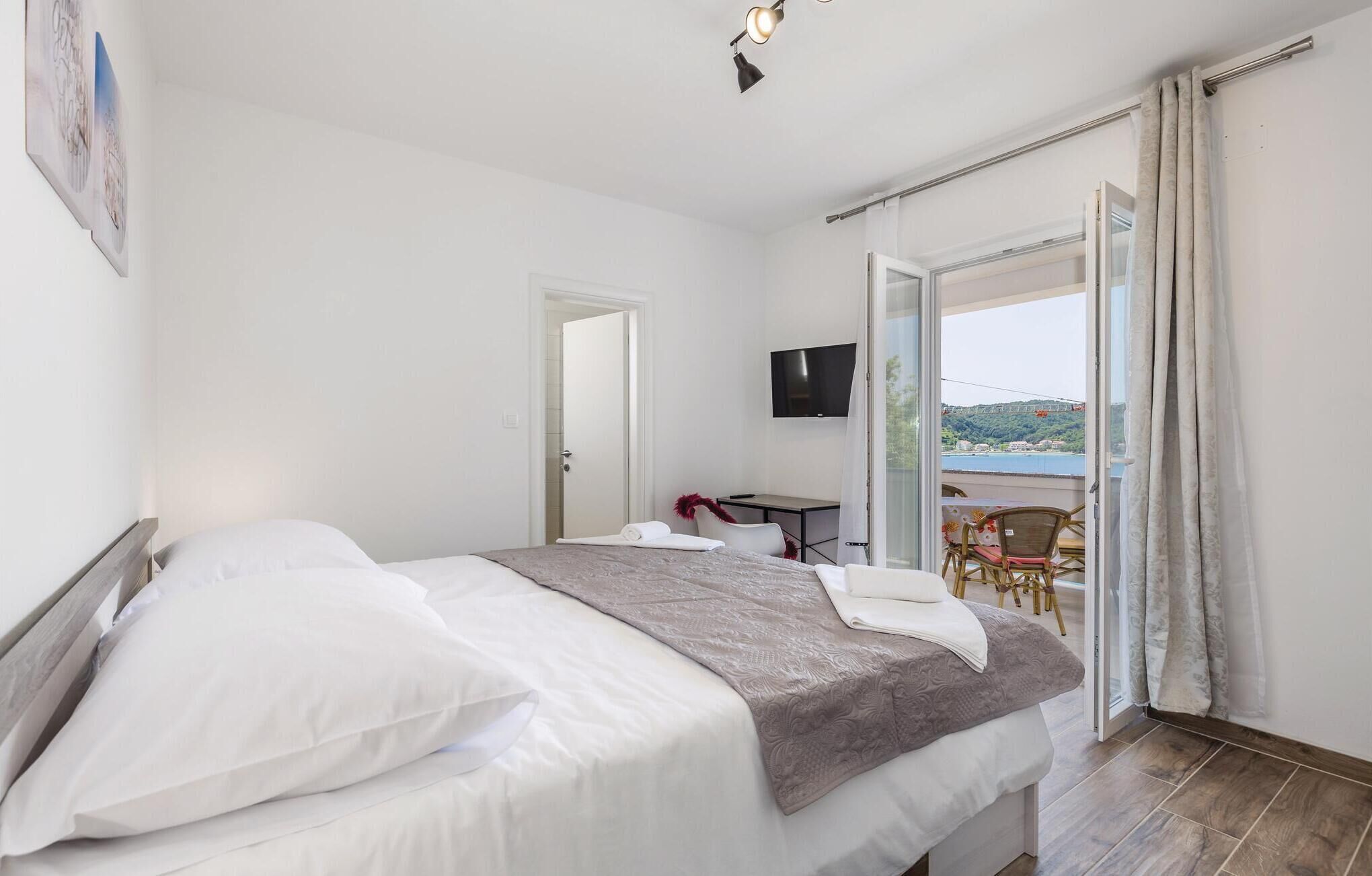 Et hotelværelse med seng, skrivebord, stol, fjernsyn og en balkon med udsigt.