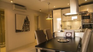 A modern kitchen with stainless steel appliances, a dining area with a table and chairs, and a pendant light. - Alcam Molino (Barcelona)
