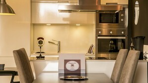 A modern kitchen with stainless steel appliances, a dining table with chairs, and a "Buenos dias" sign. - Alcam Molino (Barcelona)