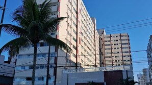 A multi-story building with a modern architectural design, featuring a prominent vertical structure and multiple balconies. - BUILDING FACING THE SEA IN PRAIA GRANDE-SP (Guilhermina)