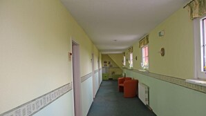 A narrow hallway with a carpeted floor, a radiator, and a staircase at the end. - Hotel Parkschänke Zabeltitz (Grossenhain)