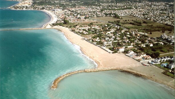 An aerial view of a coastal area with a beach, a breakwater, and residential buildings. - Nice and complete apartment in playa oliva / denia (El Verger)