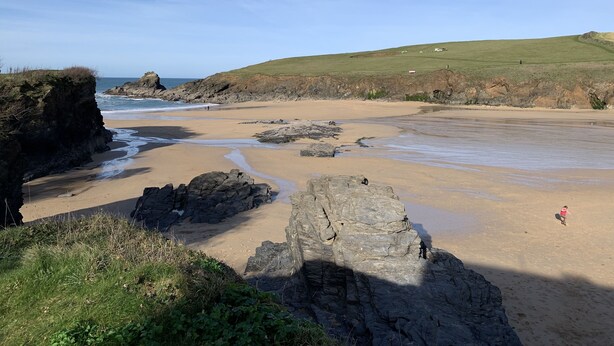 A coastal beach with rocky outcrops and a grassy hill in the background. - Perfect location for exploring the local 7 bays, Wifi, local amenities (Padstow)