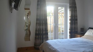 A bedroom with a bed, a nightstand, a mirror, and a door leading to an outdoor area. - Perfect location for exploring the local 7 bays, Wifi, local amenities (Padstow)