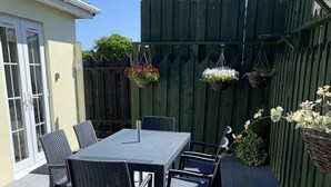 A patio with a table and chairs, a wooden deck, and a wooden fence. - Perfect location for exploring the local 7 bays, Wifi, local amenities (Padstow)