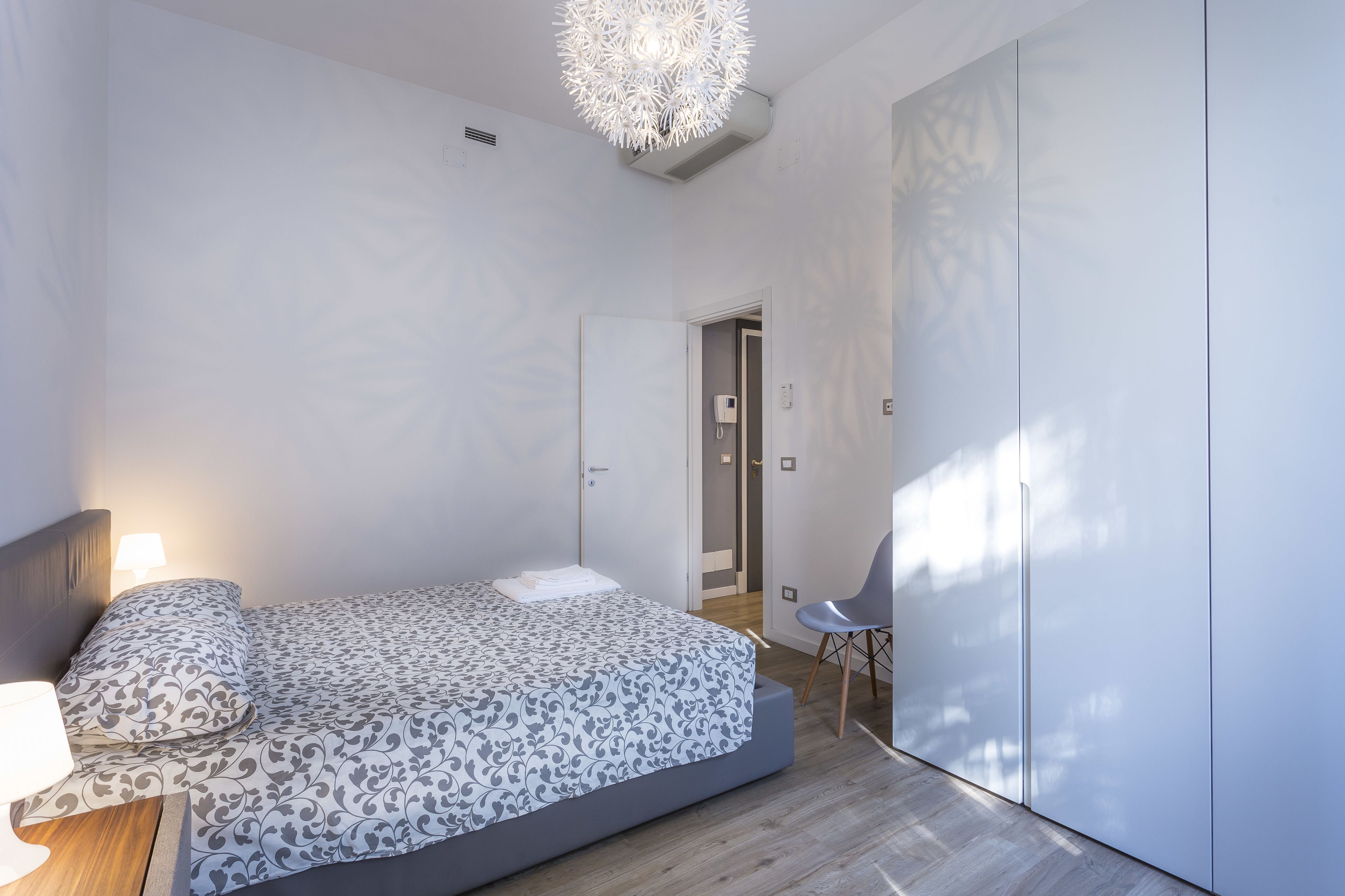 Een moderne slaapkamer met een bed, nachtkastje en een stoel.