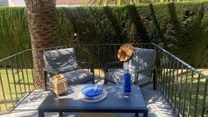 Ein Sitzbereich im Freien mit zwei Stühlen, einem Tisch und einem Zierhut.